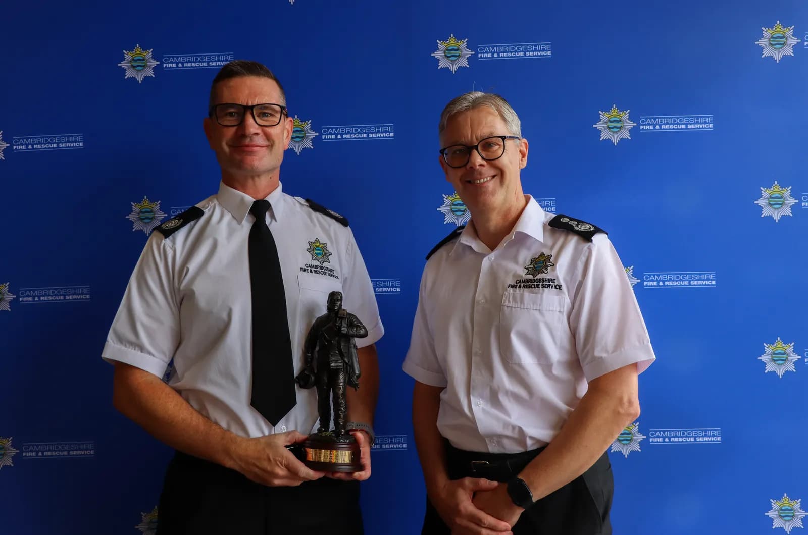 Tony receiving his retirement figurine from Matthew, along with a photo of Tony on his own, are both attached.
